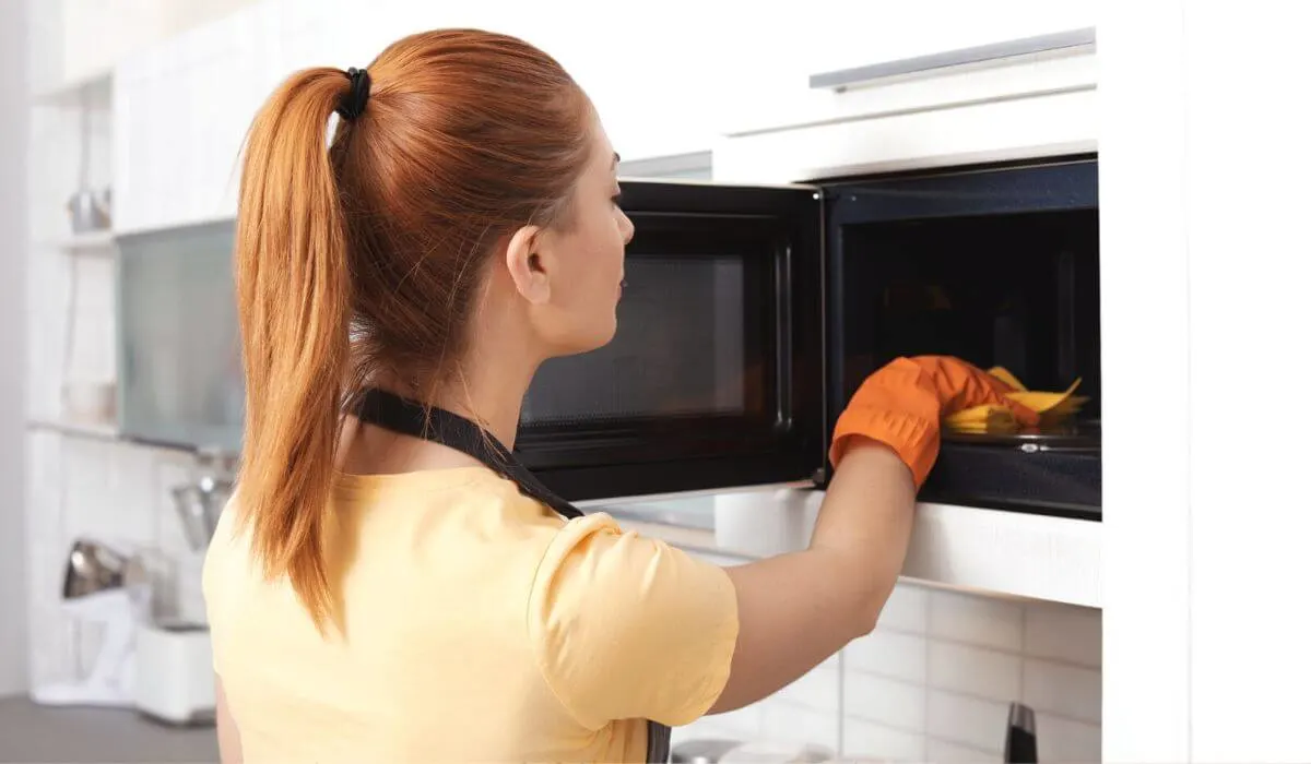 woman cleaning microwave interior