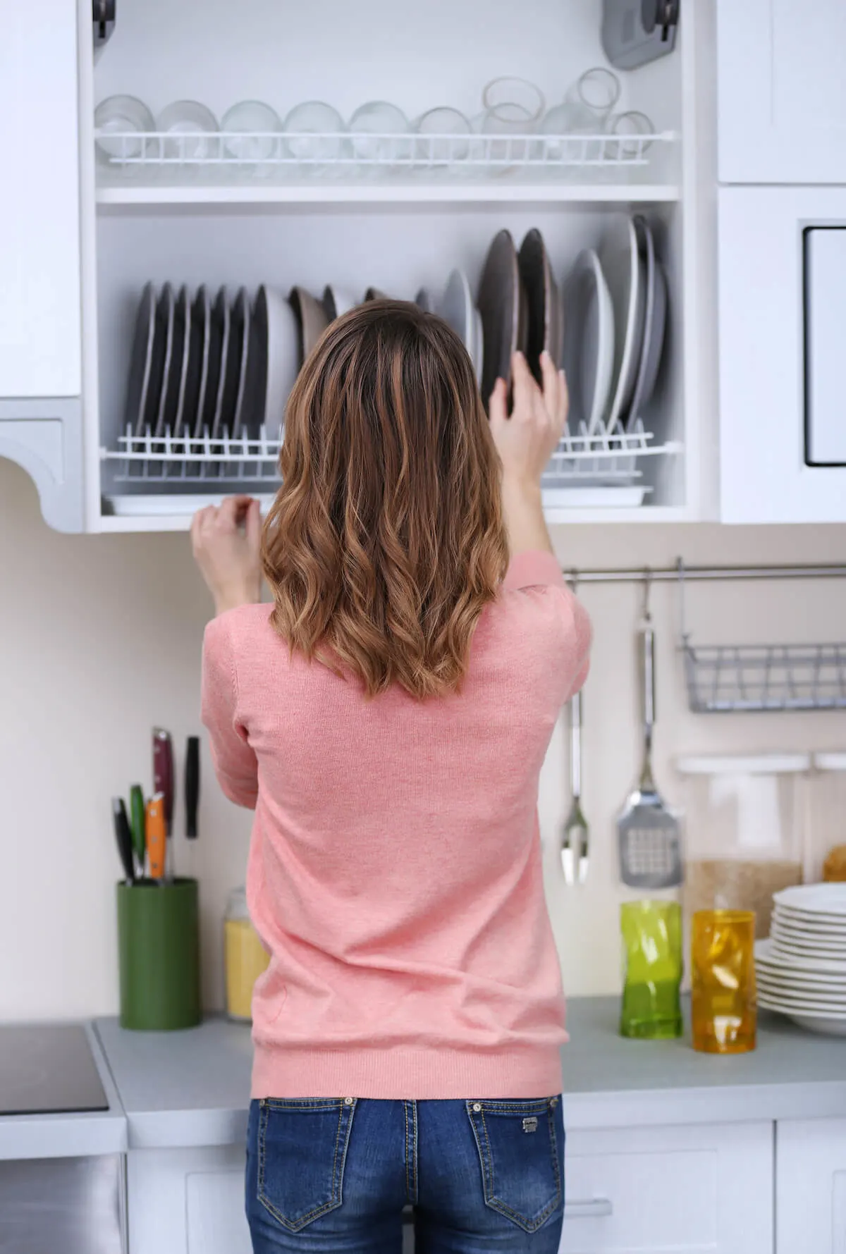 Woman sorting plates in cupboard