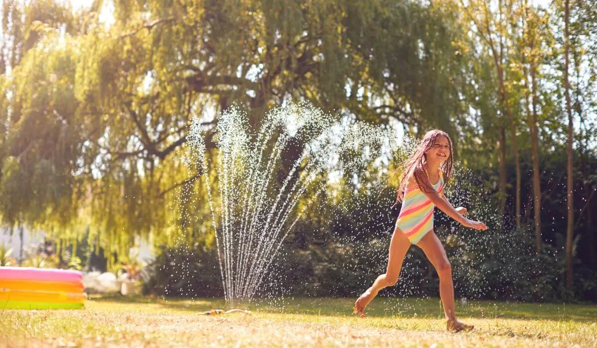 Girl playing under the sprinkler
