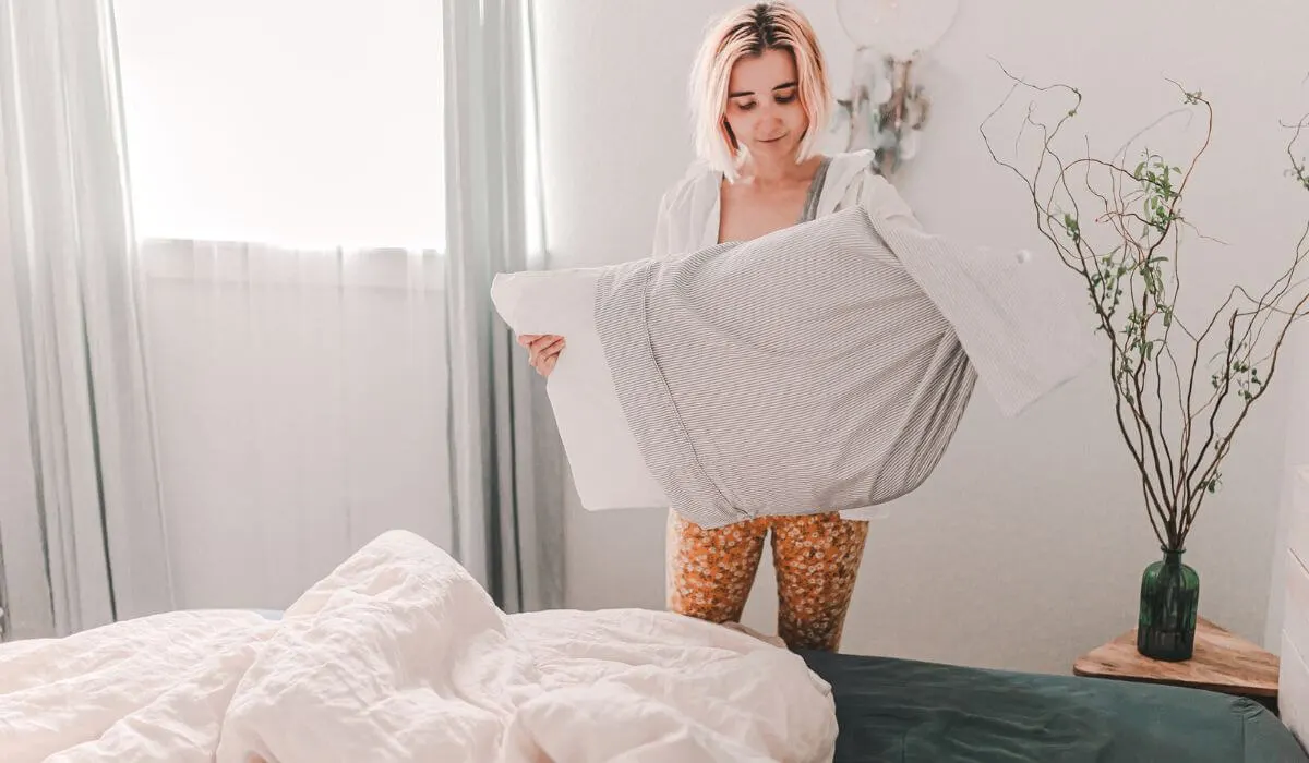 Woman changing pillowcase in bedroom