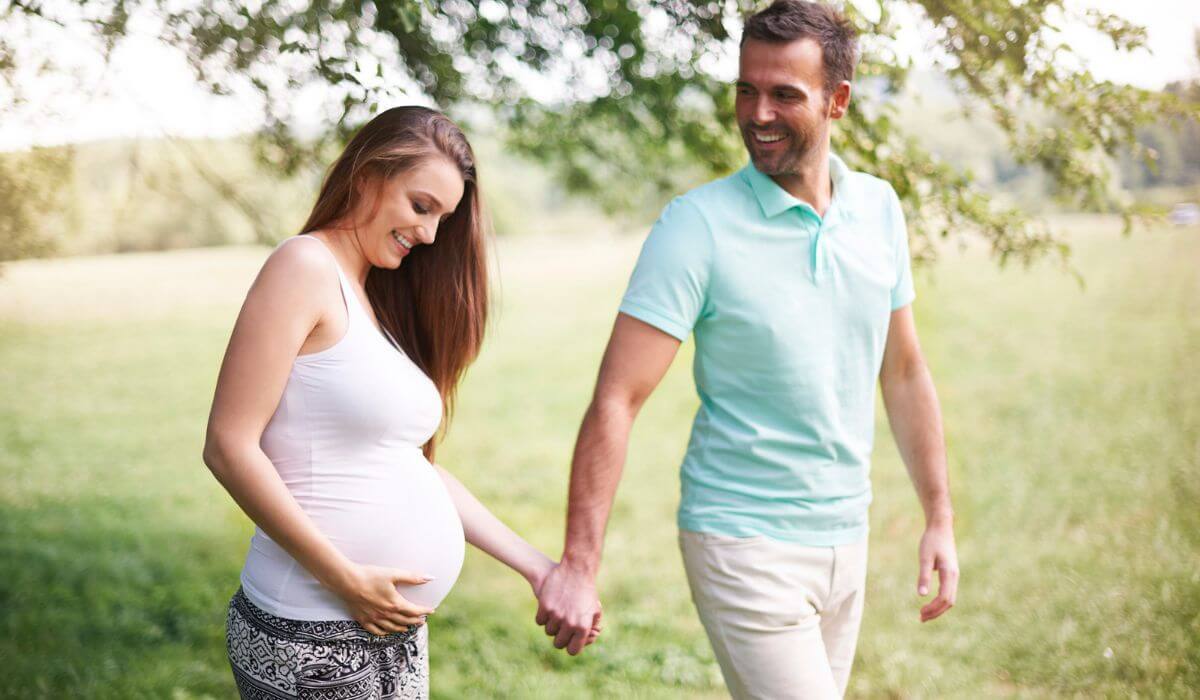 Pregnant woman holding hands with partner outdoors