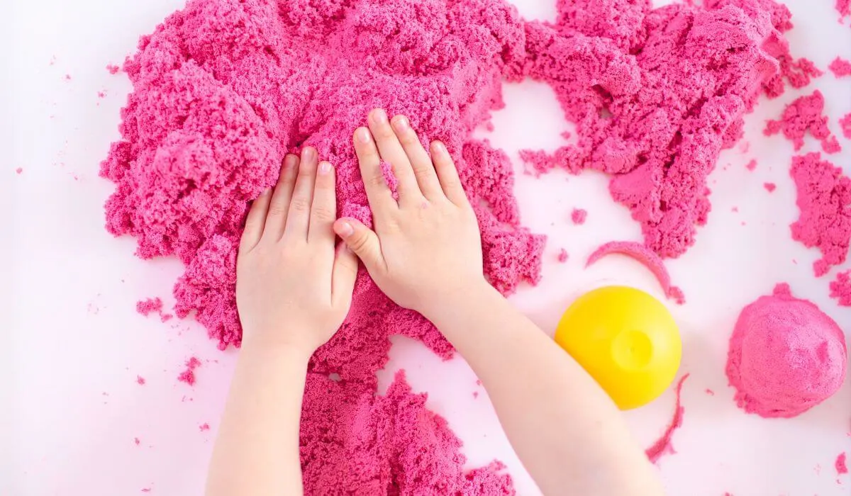 Child's hands playing with pink kinetic sand