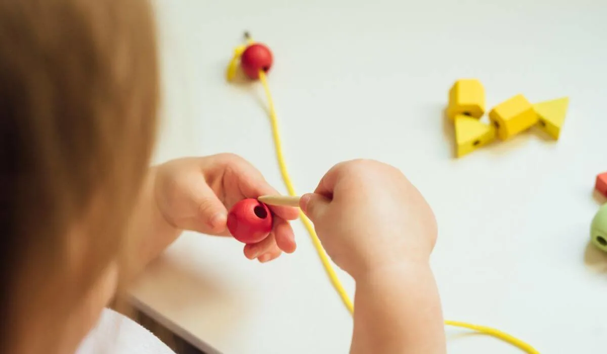 Toddler putting bead on string