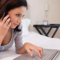woman on phone looking at laptop