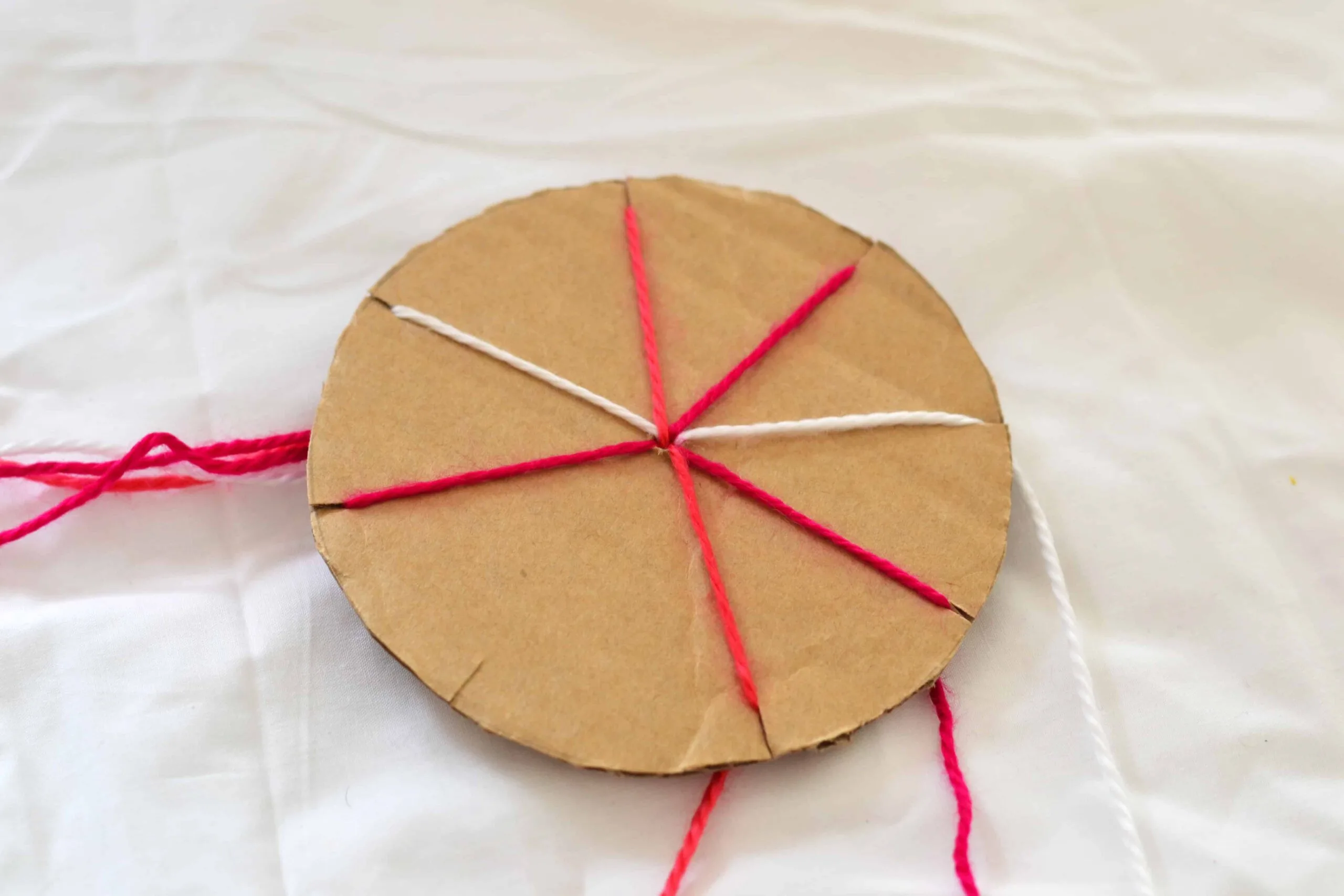 Cardboard wheel with different coloured wool to start making a friendship bracelet