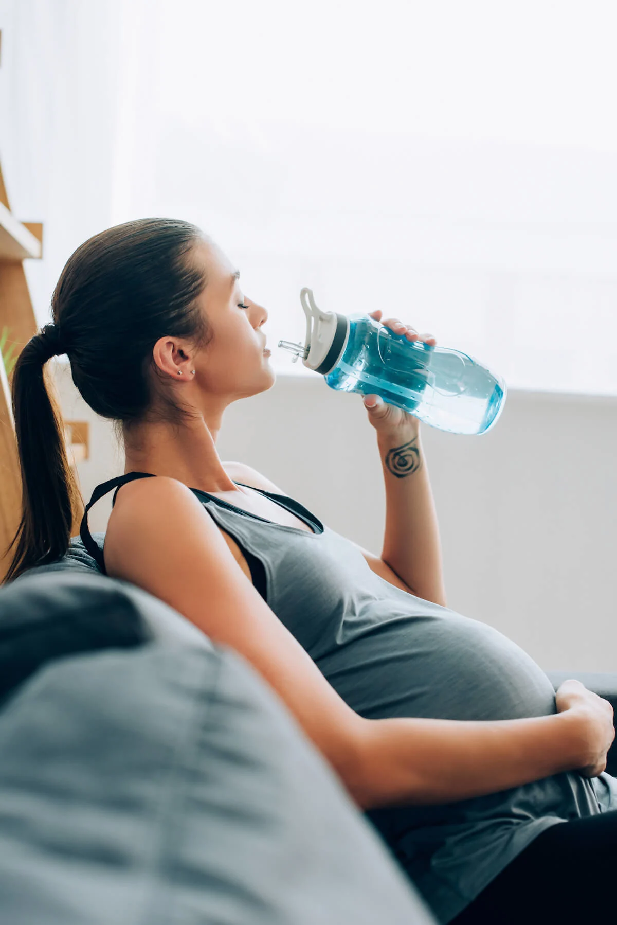 Pregnant woman on couch with water bottle