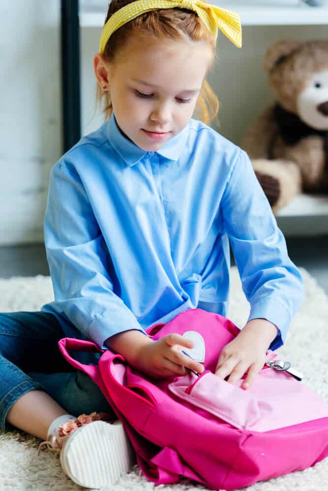 Girl practising how to open and pack her school bag
