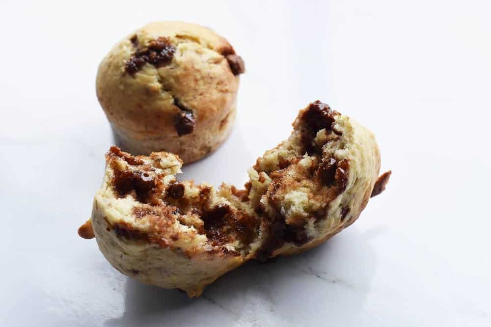 Chocolate chip banana muffins with one pulled apart to show melted chocolate.