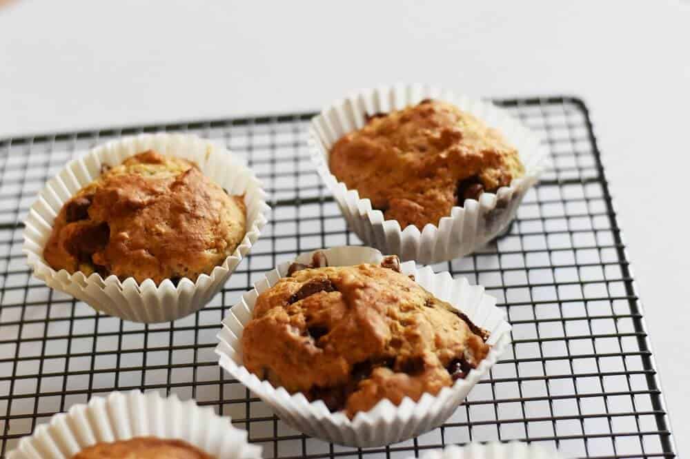 Moist Banana Chocolate Chip Muffin Recipe 6 Banana choc chip muffins in cupcake pans on a cooling rack.