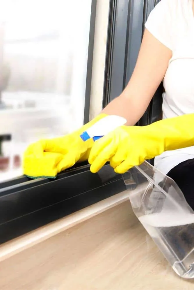 Person cleaning window tracks with sponge