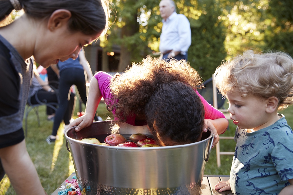 35 Fun Halloween Party Games For Kids & Adults 3 kids bobbing for apples at a halloween party.