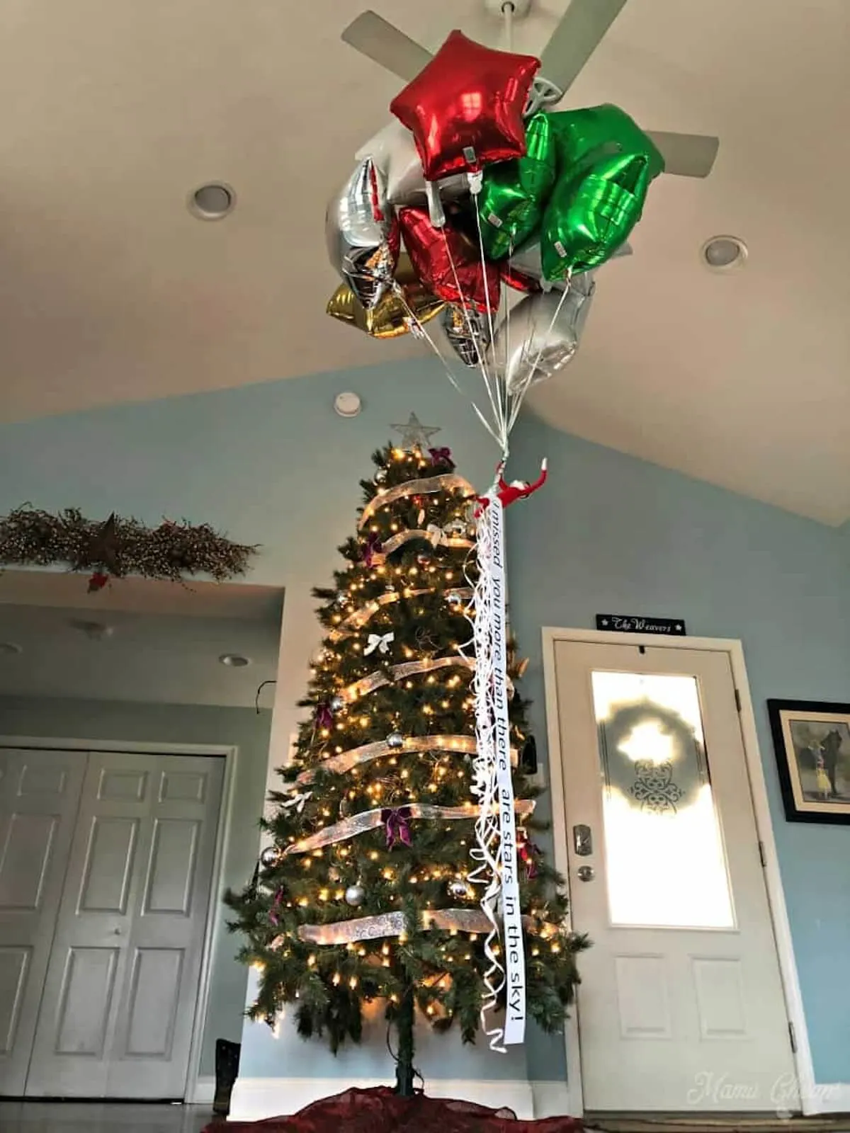 Elf arrival balloon scene hanging next to christmas tree.
