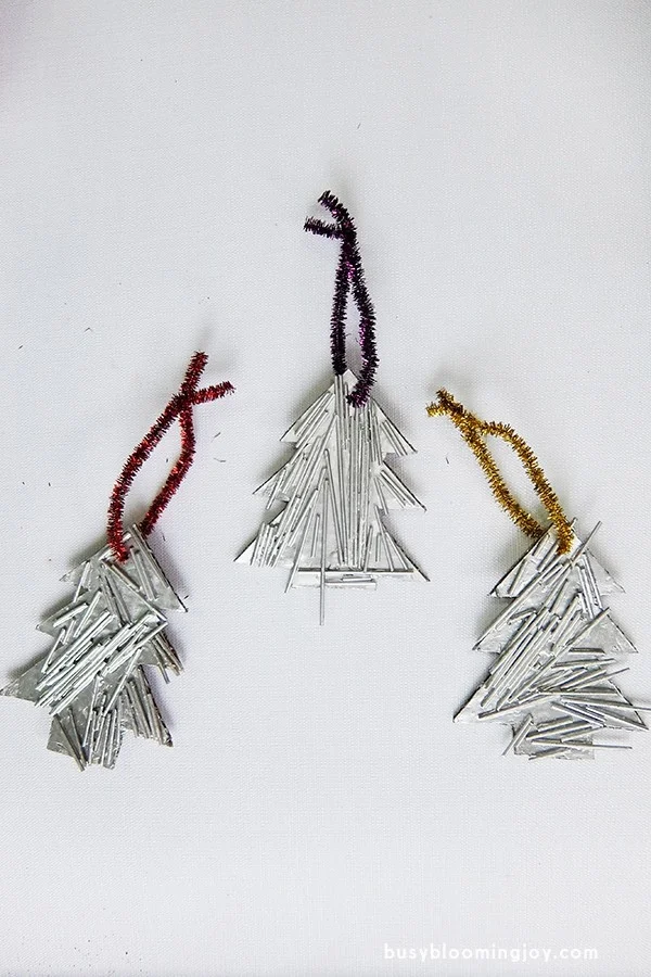 3 handmade silver pasta christmas tree ornaments on a white background.
