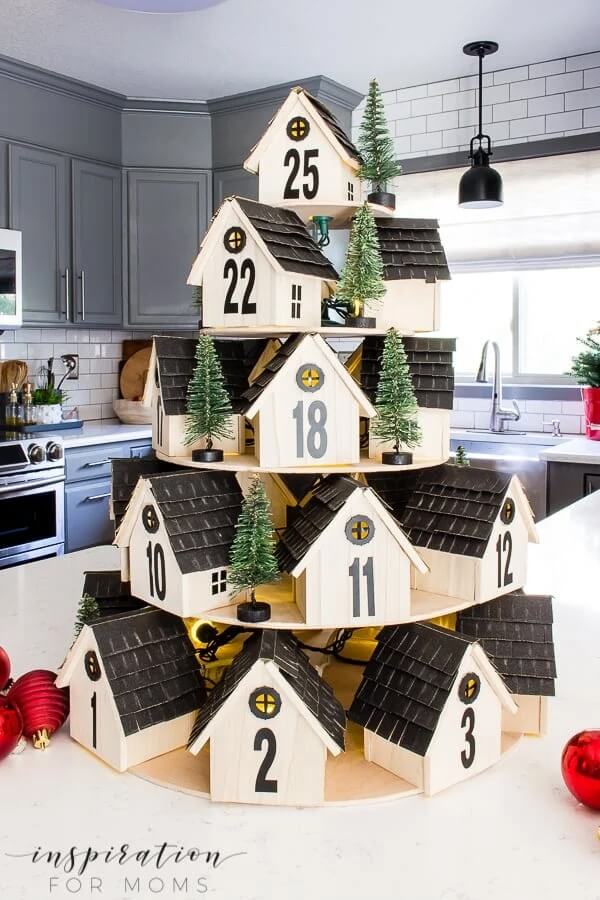 Tiered wooden advent houses sitting on a bench.