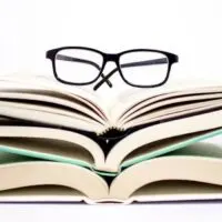 books about decluttering stacked with reading glasses