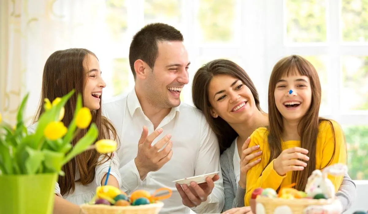 Family laughing together while painting easter eggs