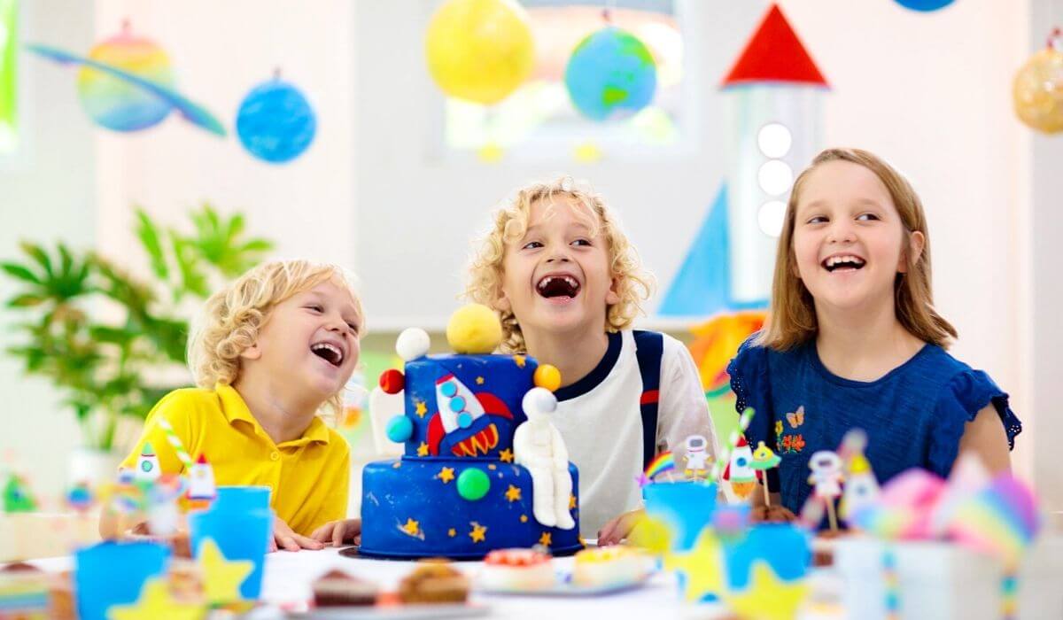 Space party theme with three kids around a cake