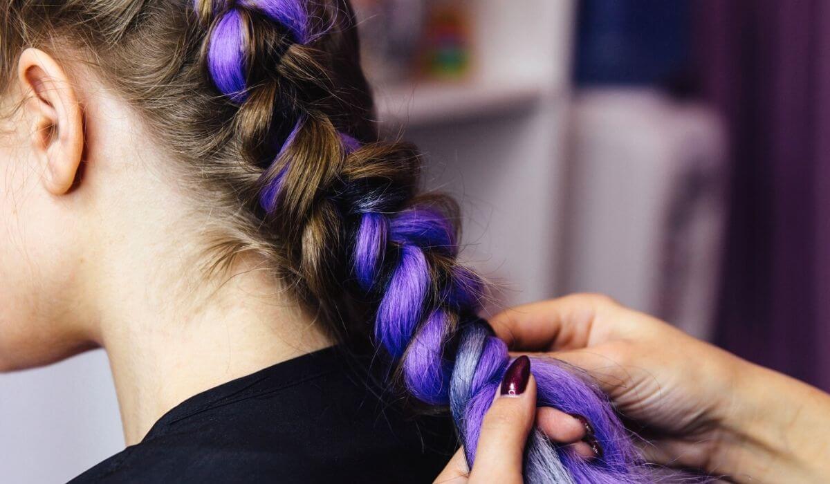 Girl getting her hair braided with purple extensions