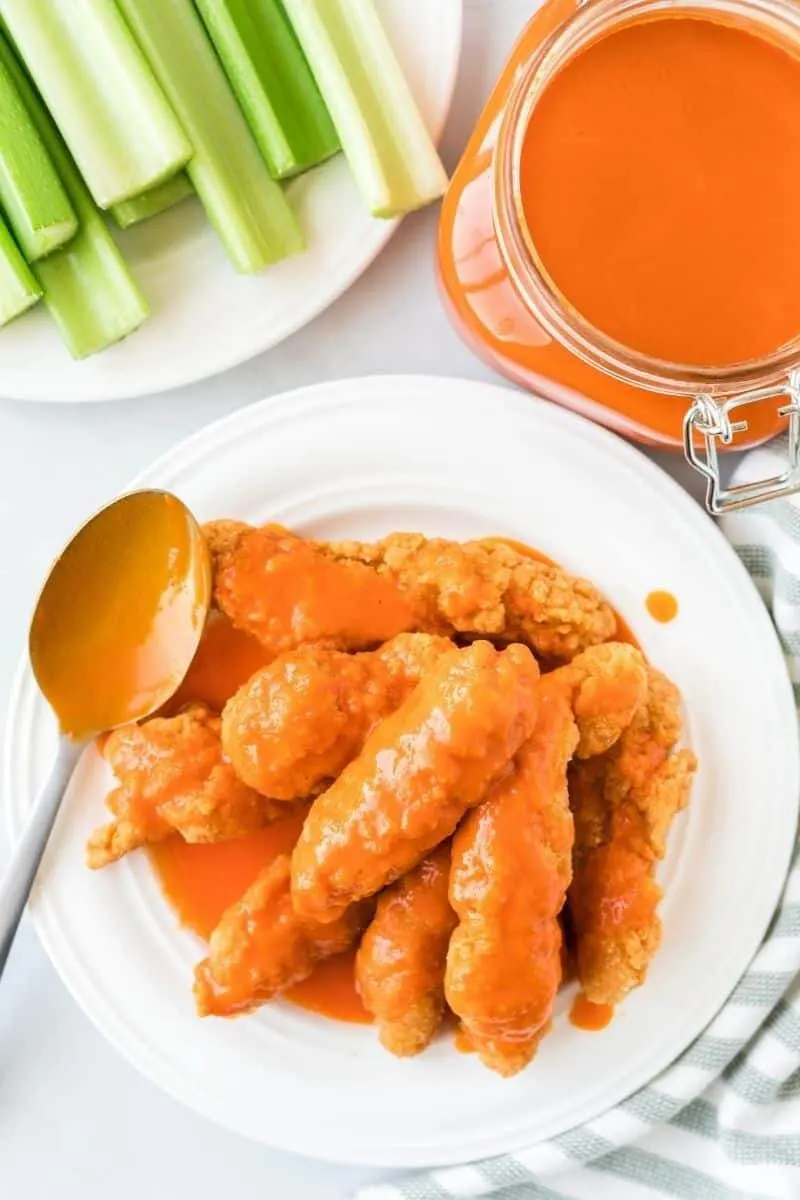 Homemade buffalo sauce pouring over wings