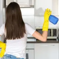 woman standing in front of kitchen with cleaning spray