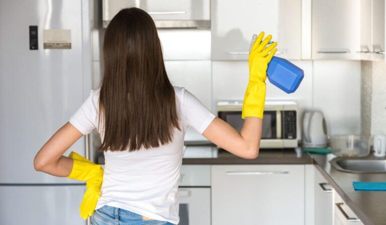 Woman standing in front of kitchen with cleaning spray