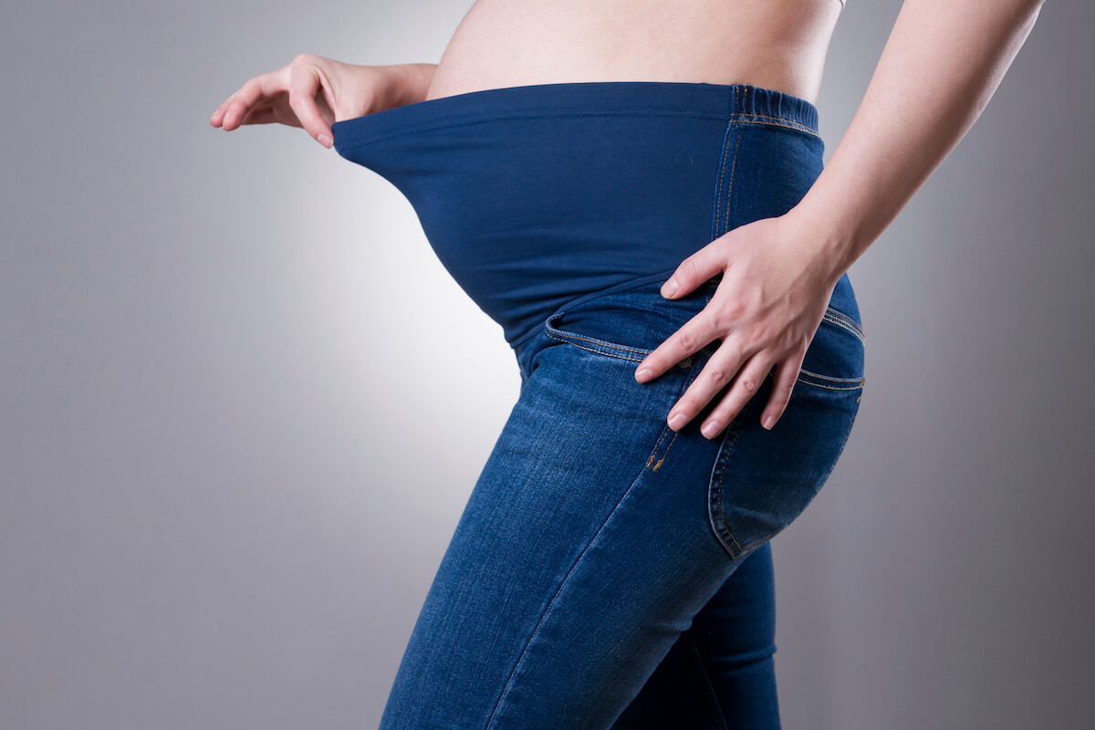 A woman wearing maternity jeans with a blue belly band