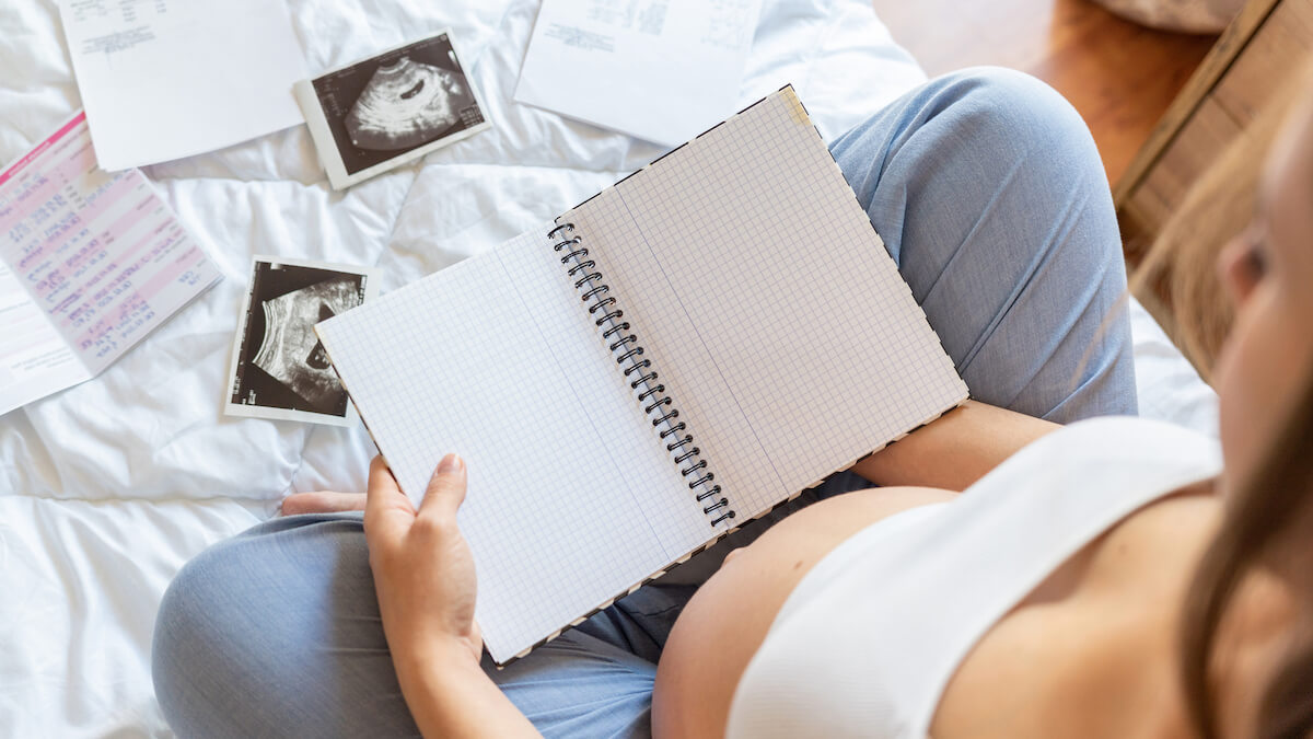 A woman filling in her pregnancy journal with ultrasound photos