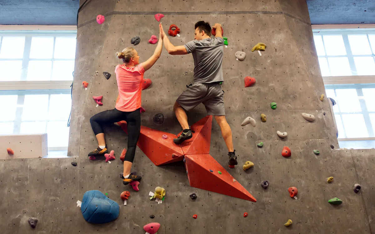 Couple giving each other a high five while doing indoor rock climbing