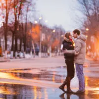 couple cuddling in the rain on a street