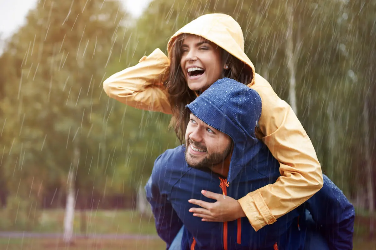 man giving woman piggyback in the rain