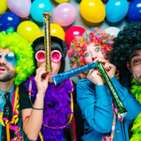 group of friends dressed up for a thene party with wigs and balloons