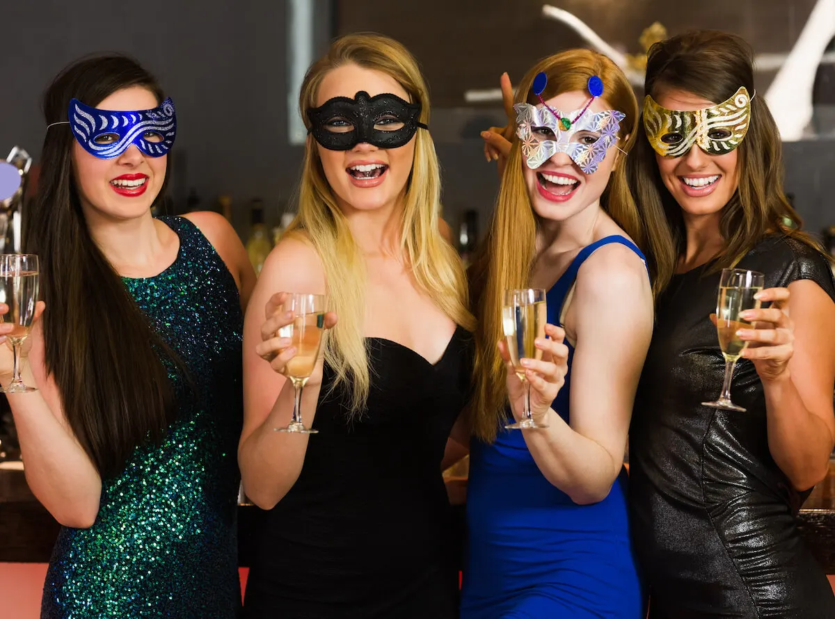 Four women with masquerade masks on