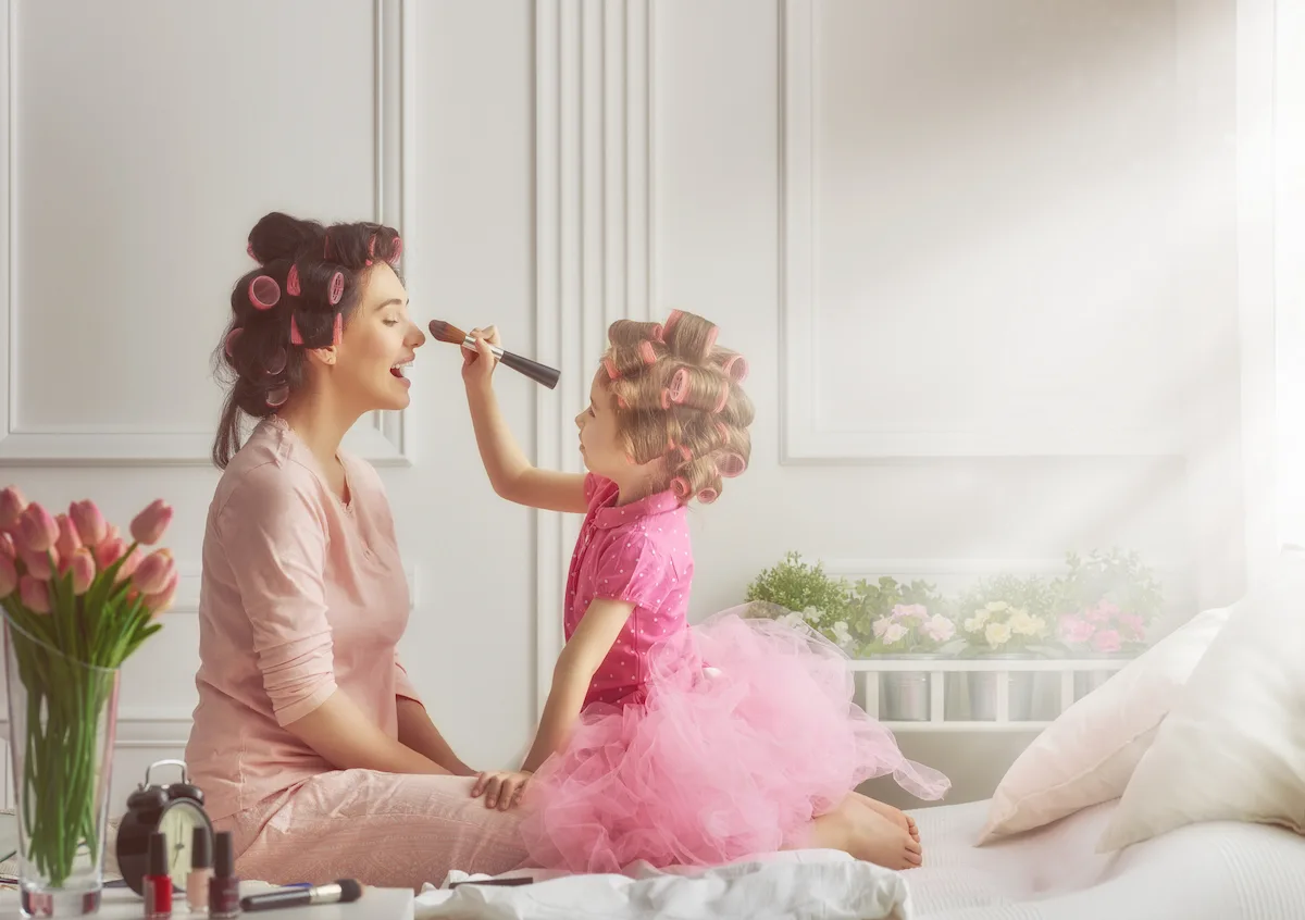Mother and daughter doing makeup sitting on the bed