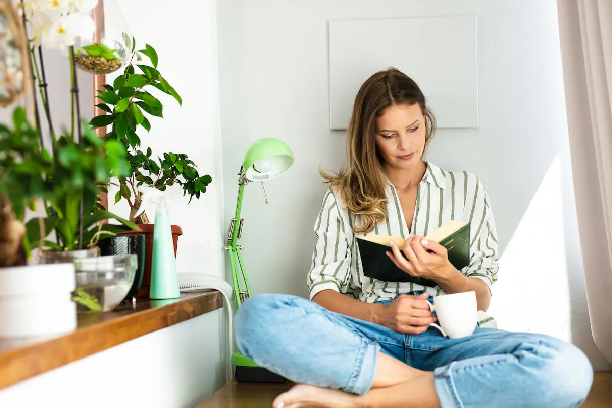 woman reading a book with a cup of coffee in hand