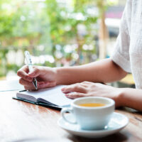 woman in cafe writing in journal