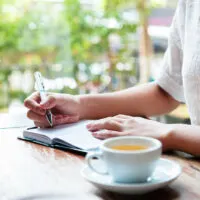 woman in cafe writing in journal