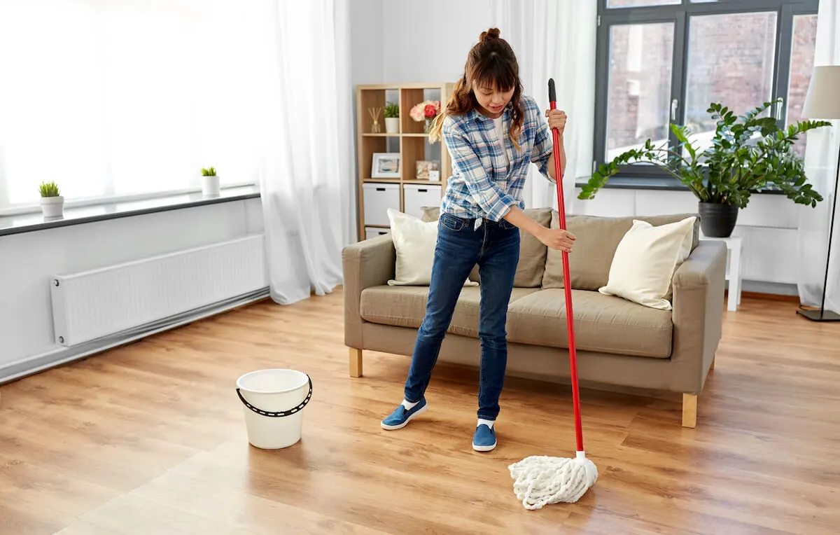 teenage girl mopping polished wooden floorboards