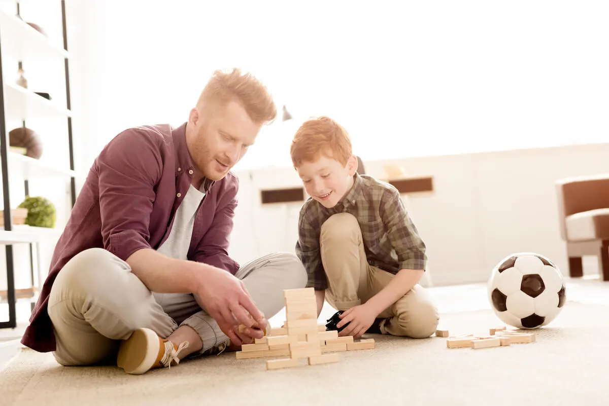 Father and son sitting on the carpet playing a block building game