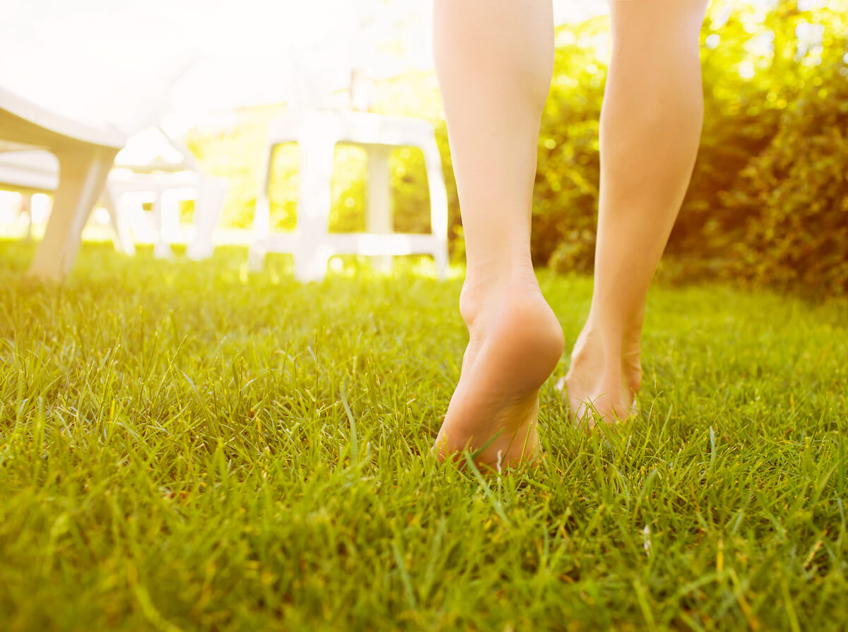 Woman walking barefoot on grass on a sunny day