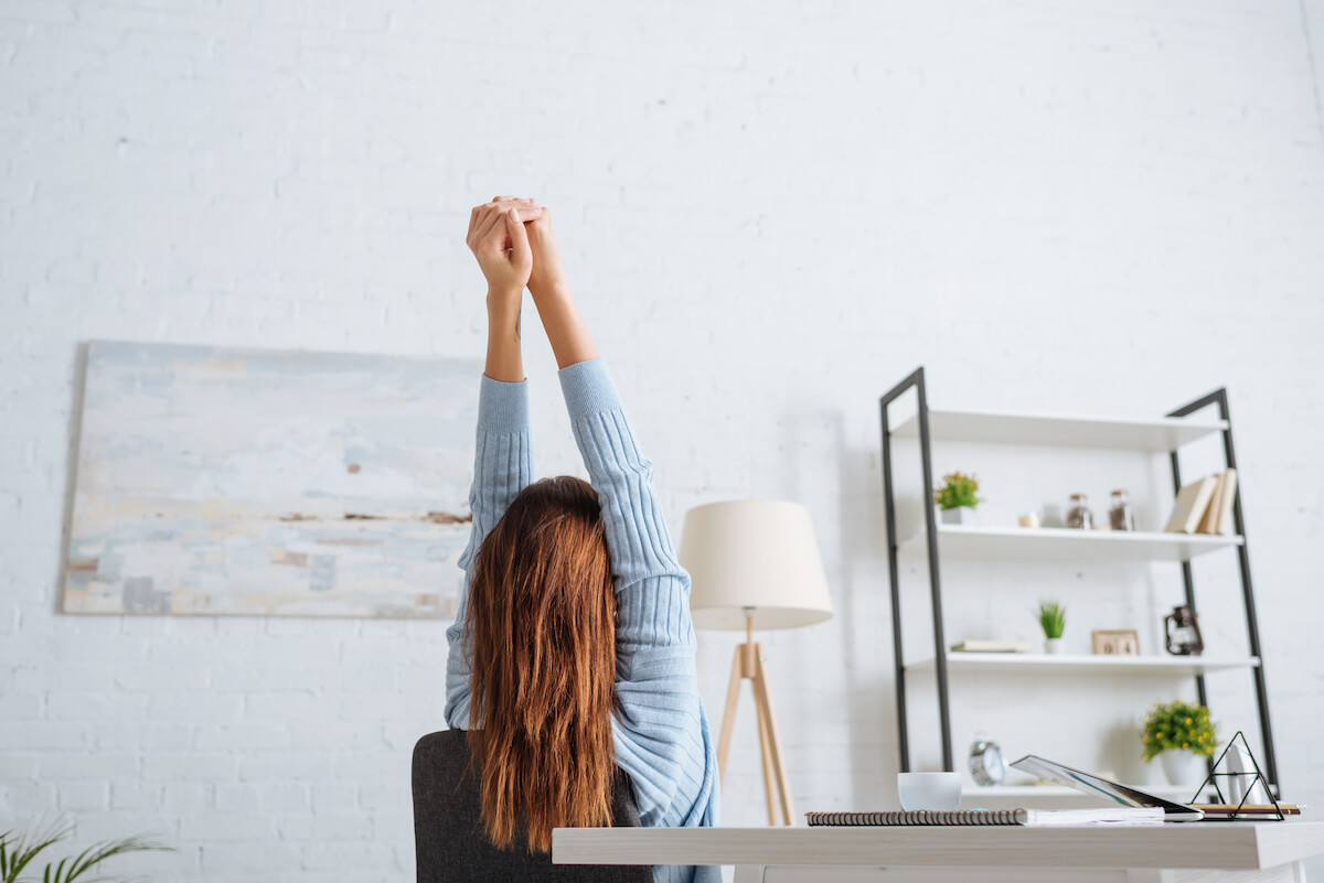 Woman stretching at her desk in a tidy minimalist office