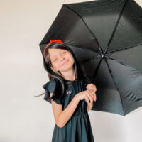little girl dressed up as morrigan crow with open umbrella