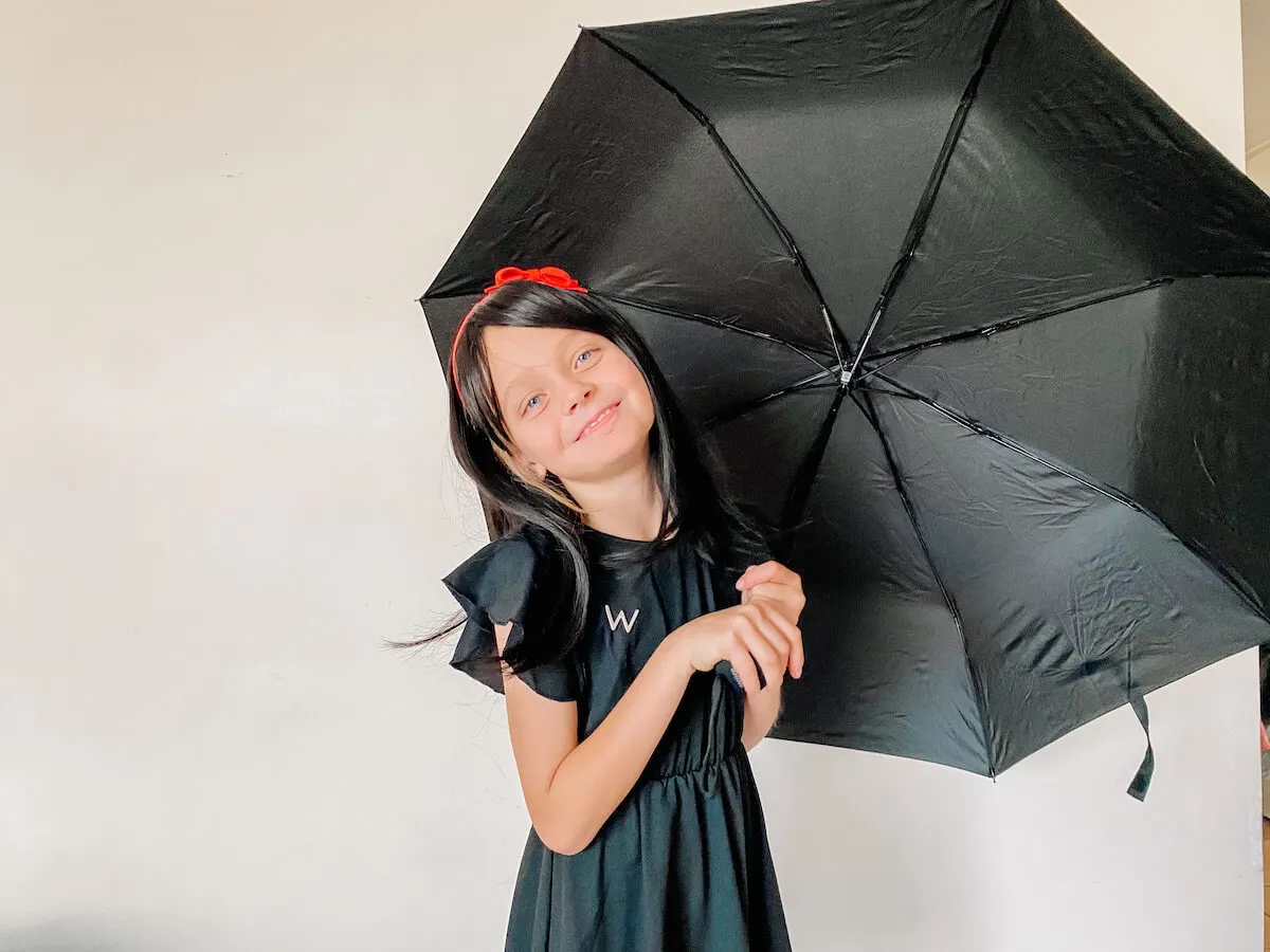 Little girl dressed up as morrigan crow with open umbrella