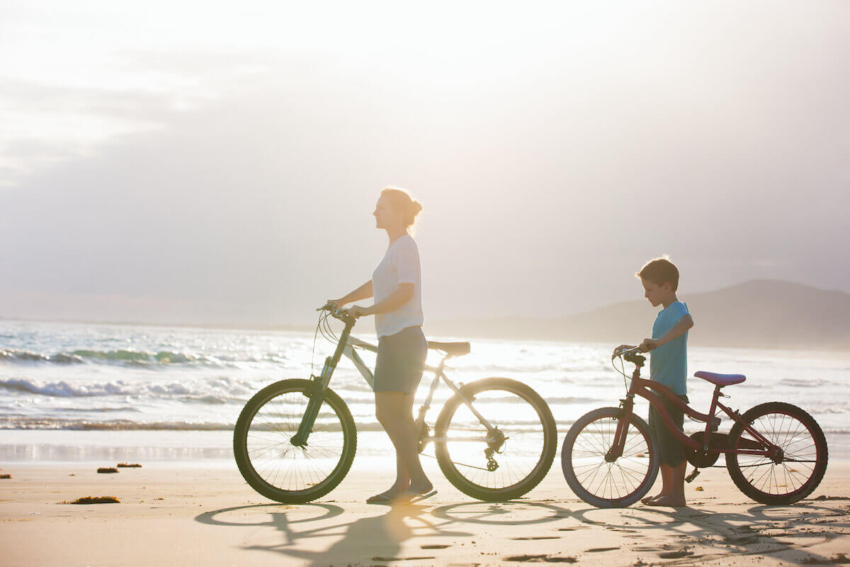 Mother and son riding bikes on the beach early in the morning