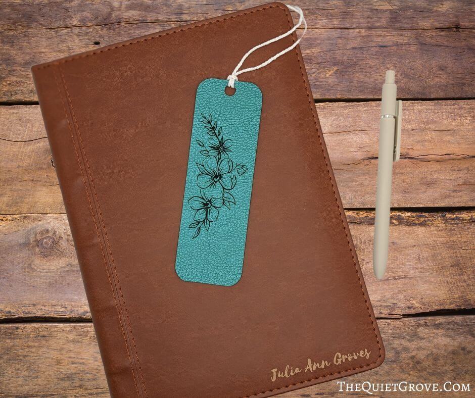 Engraved teal leather bookmark on top of a leather book