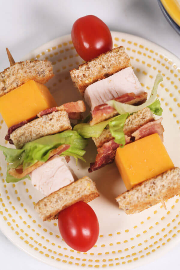 Two turkey club sandwich kabobs on a plate