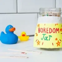 boredom jar sitting on a white benchtop with 2 rubber ducks nearby