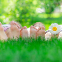 three people lying on the grass so you can see the base of their feet