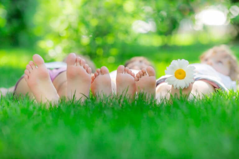three people lying on the grass so you can see the base of their feet