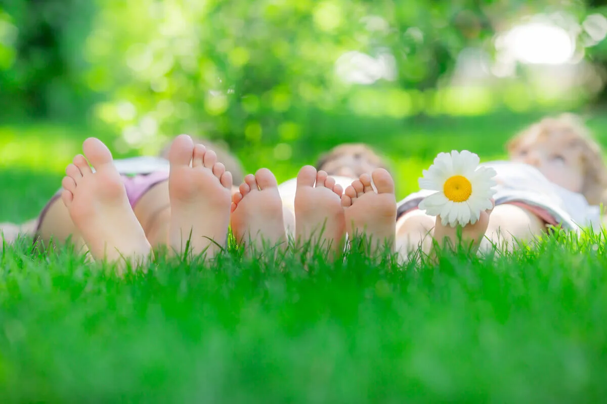 three people lying on the grass so you can see the base of their feet