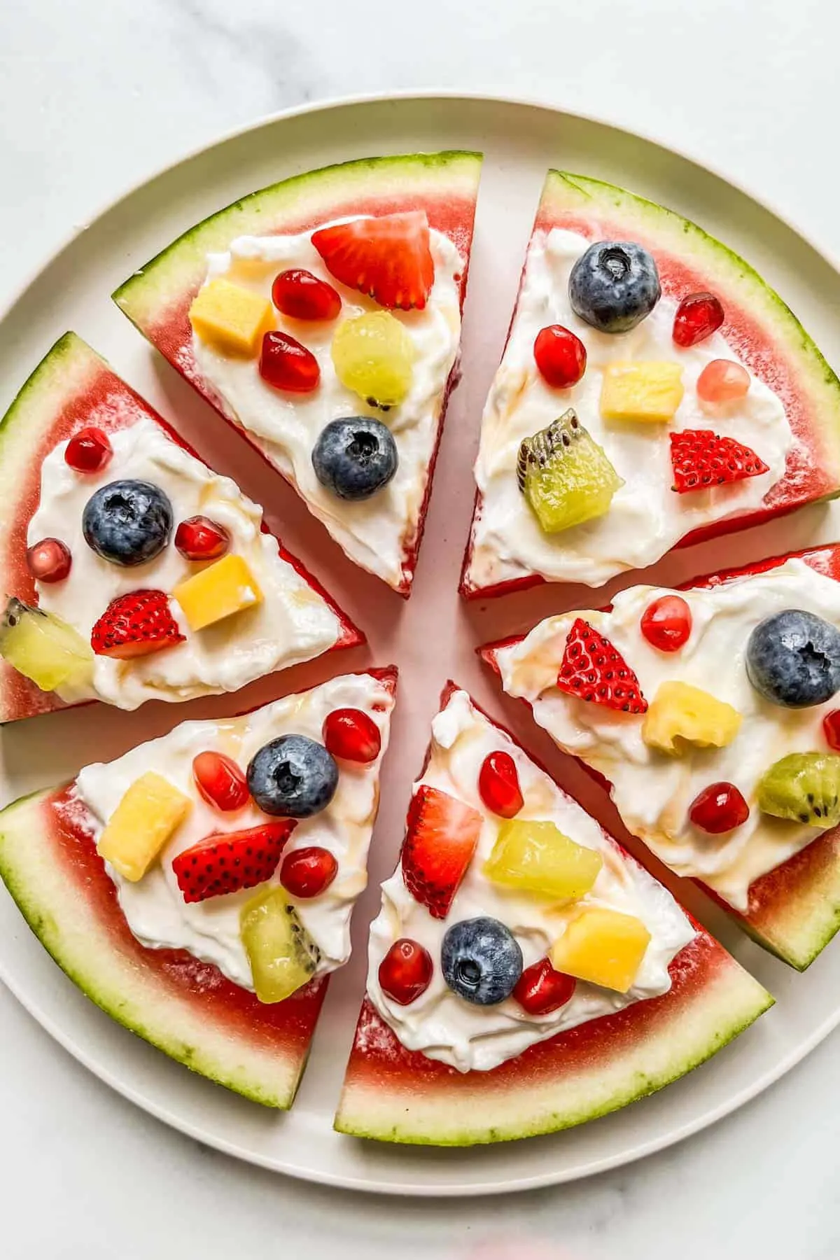 Watermelon spices topped with yogurt and fruit pieces like a pizza